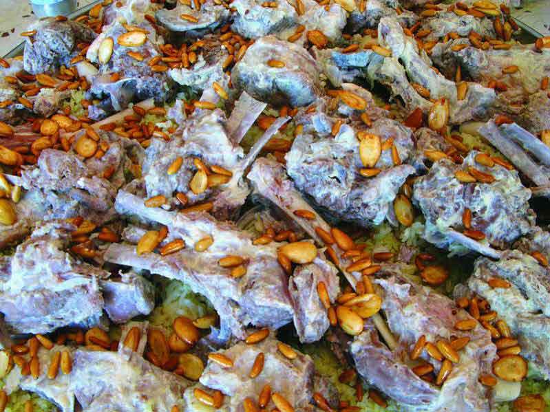 A traditional Jordanian mansaf dish served on a large communal platter with rice, lamb, and jameed sauce